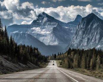 cars driving down road towards mountains